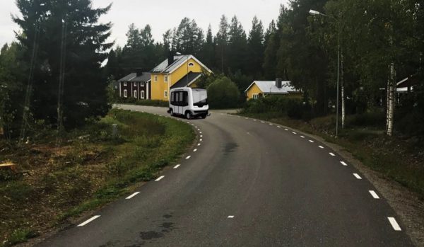 Landsväg med en liten buss går förbi hus i skogen