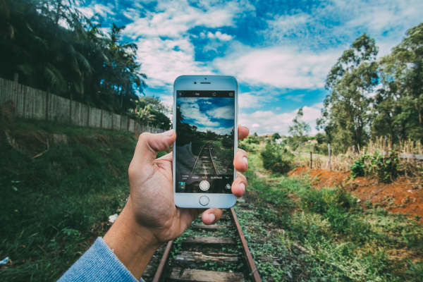 Person tar bild på sin telefon som tar bild på gammal järnväg